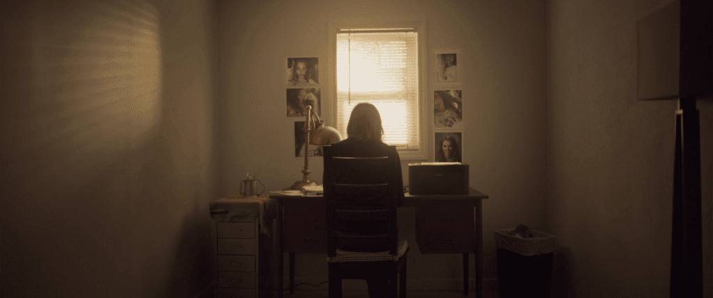 a young woman works at a desk near a bright window