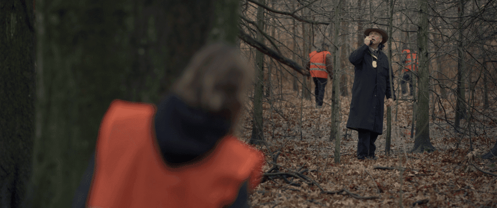 A woman in an orange safety vest watches a police officer use his radio