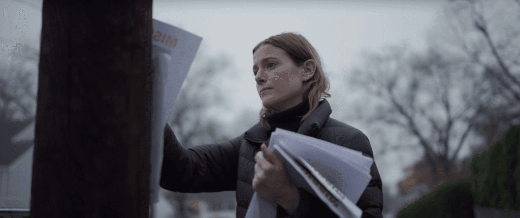A young woman attaches a leaflet to a telephone pole.